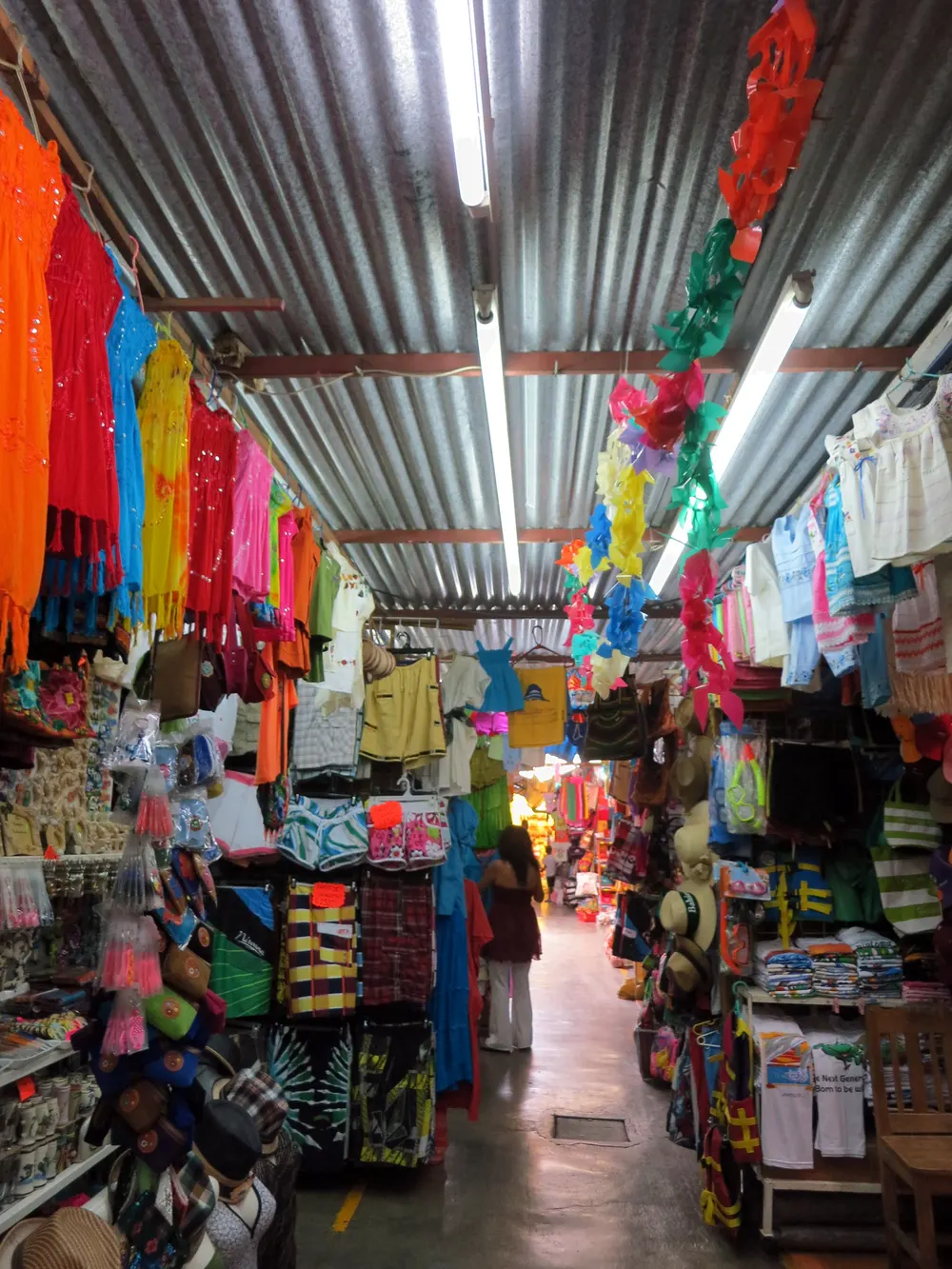 Pasillo de un mercado municipal con ropa colgada.